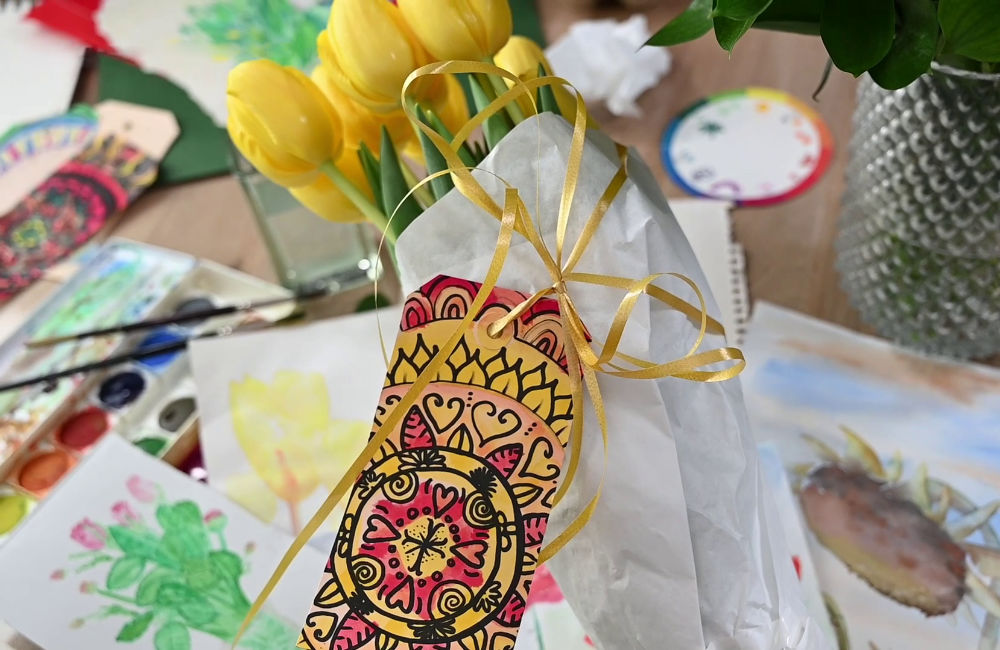 Bosje gele tulpen ingepakt met wit papier, getekende kaart en geel lint